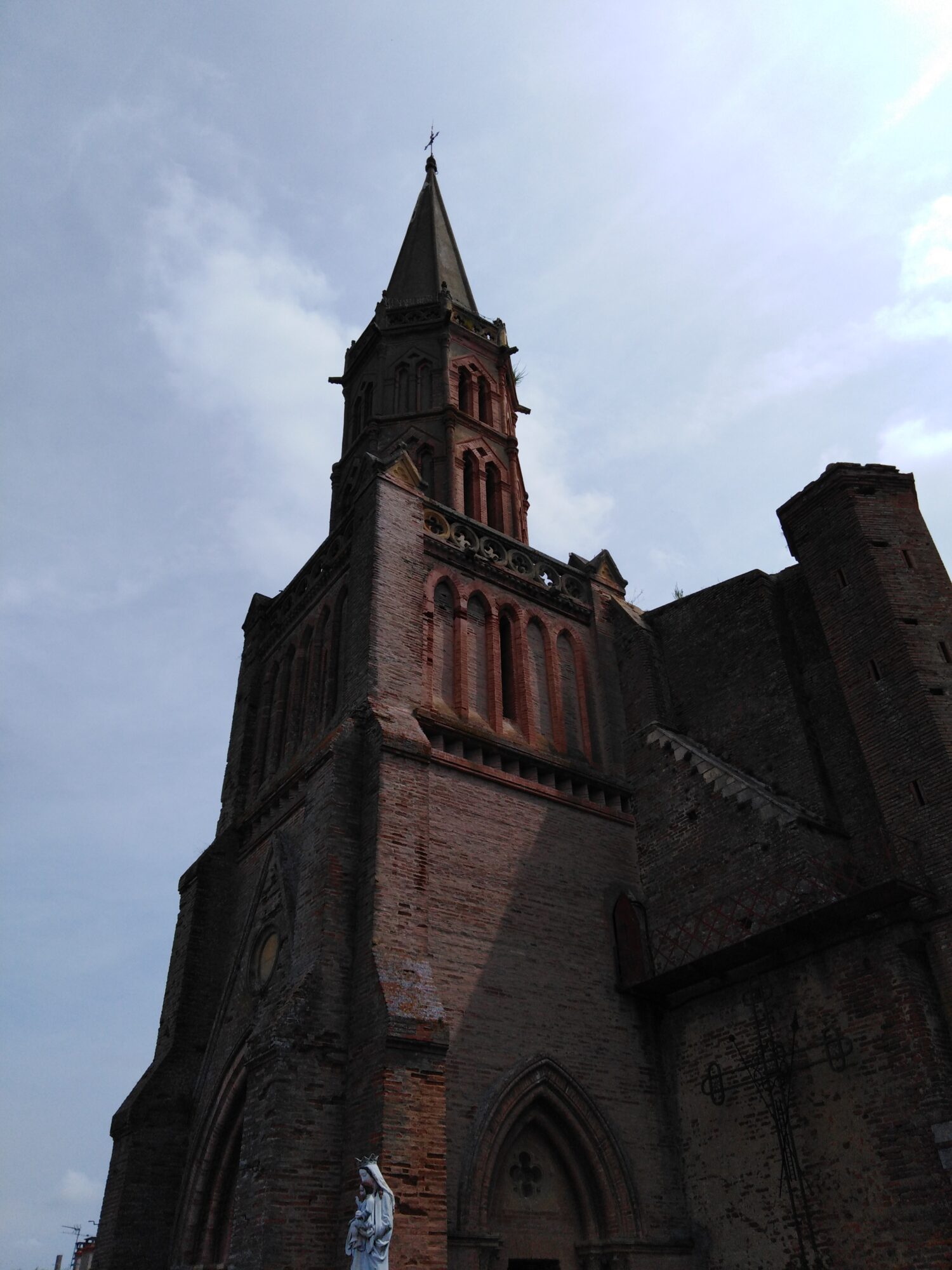 Clocher d’église en brique vu en contre-plongée, Office de Tourisme Cœur de