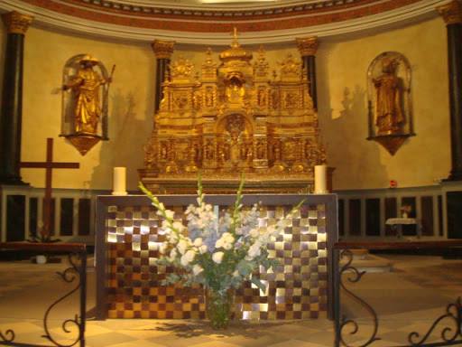 Autel d’église avec retable doré et bouquet de fleurs blanches