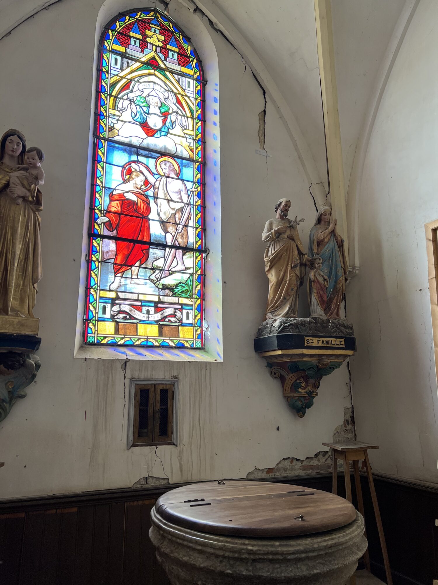 Vitrail religieux et statue de la Sainte Famille dans une église