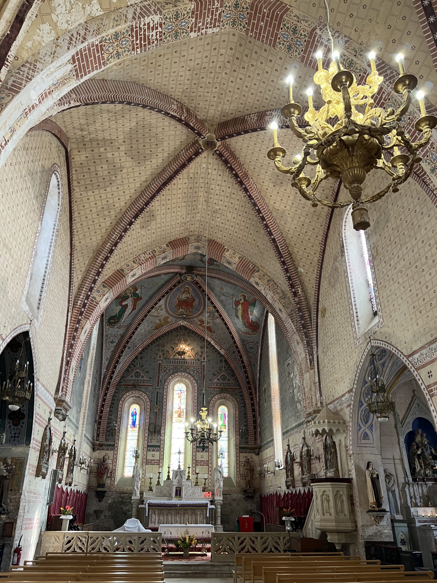 Intérieur d’église avec voûtes peintes, autel et vitraux en Cœur de Garonne