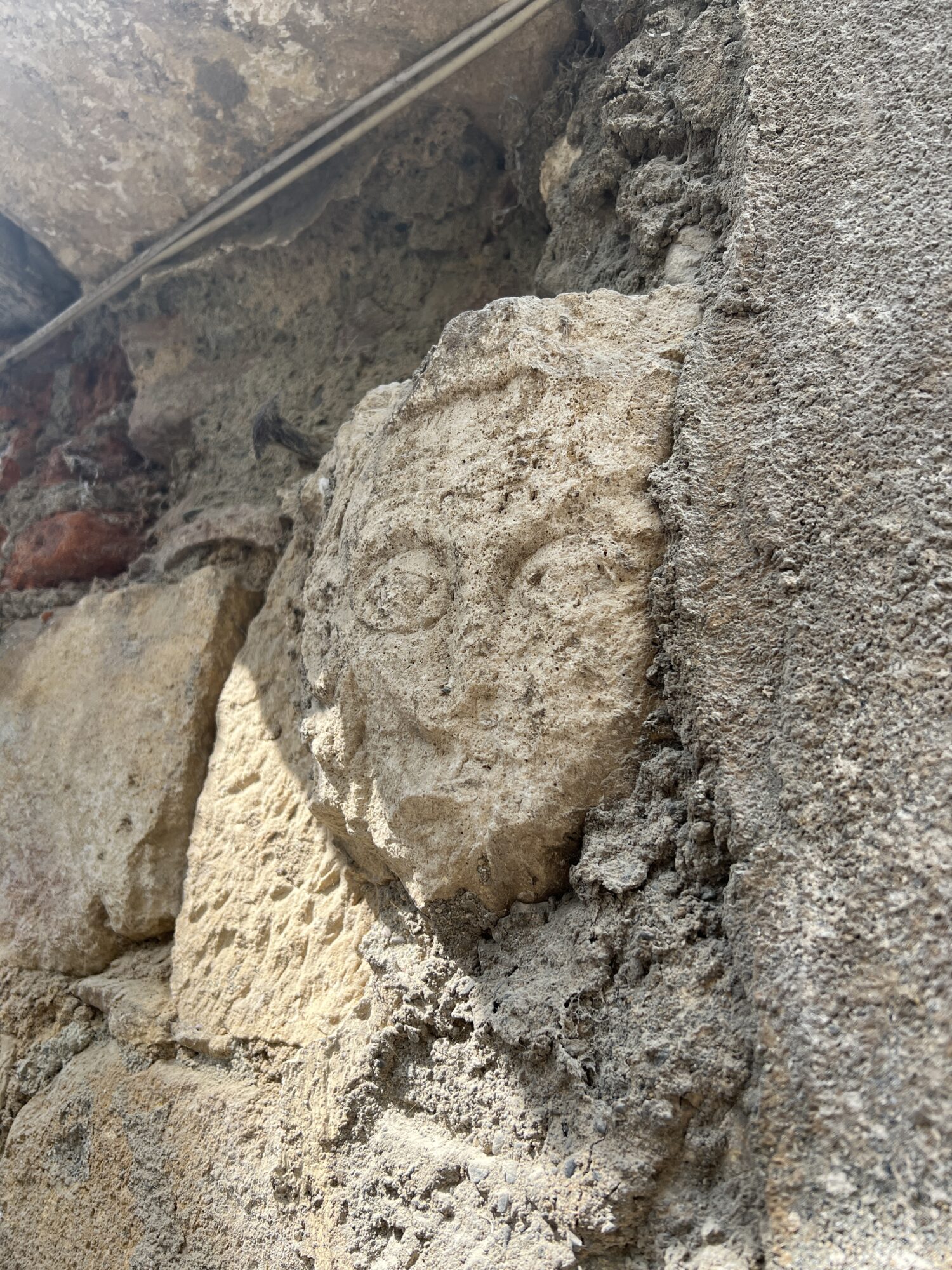 Visage sculpté en pierre sur un mur ancien, Office de Tourisme Cœur de Garonne