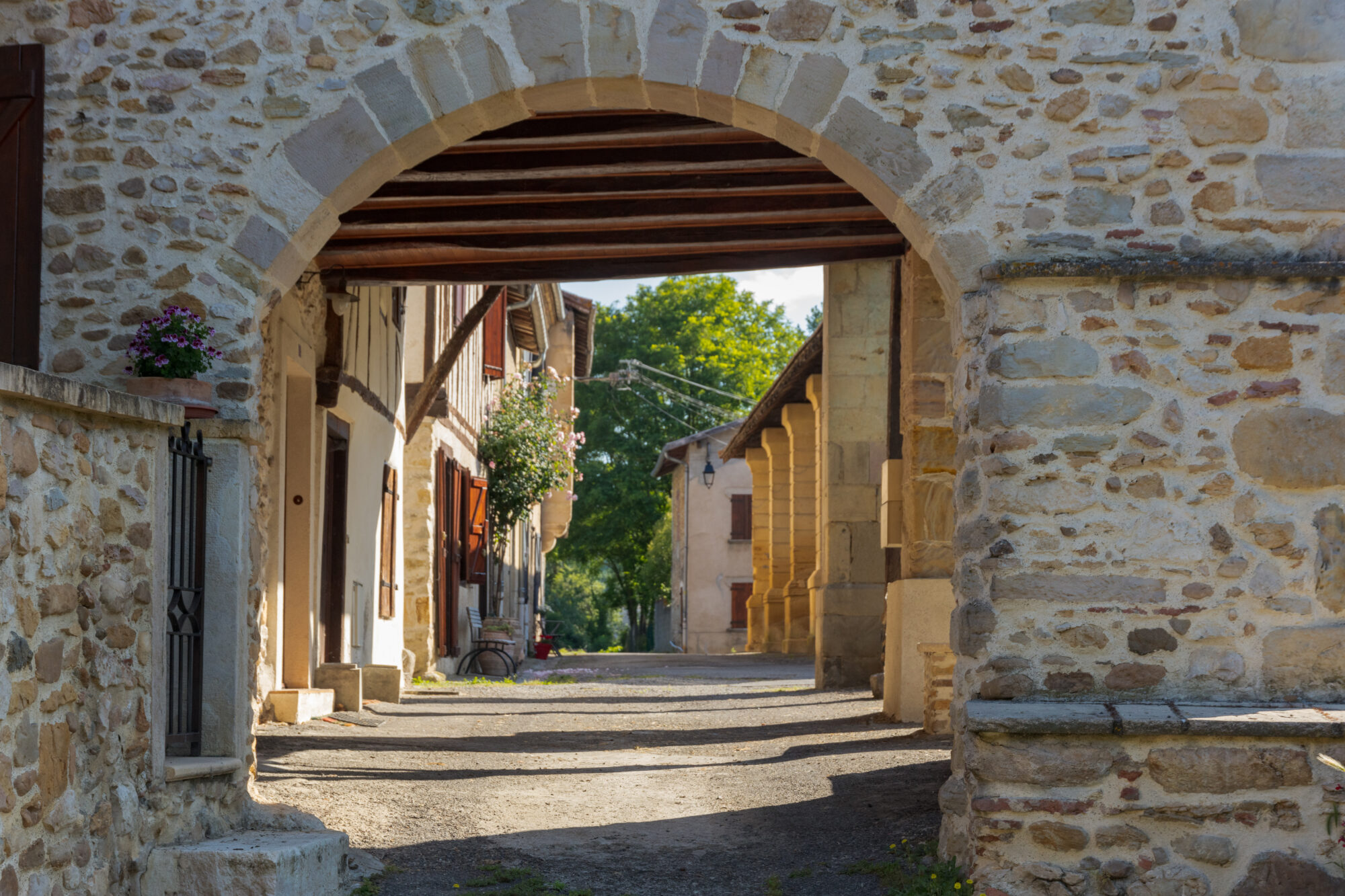 Rue de village sous une arche en pierre, Office de Tourisme Cœur de Garonne
