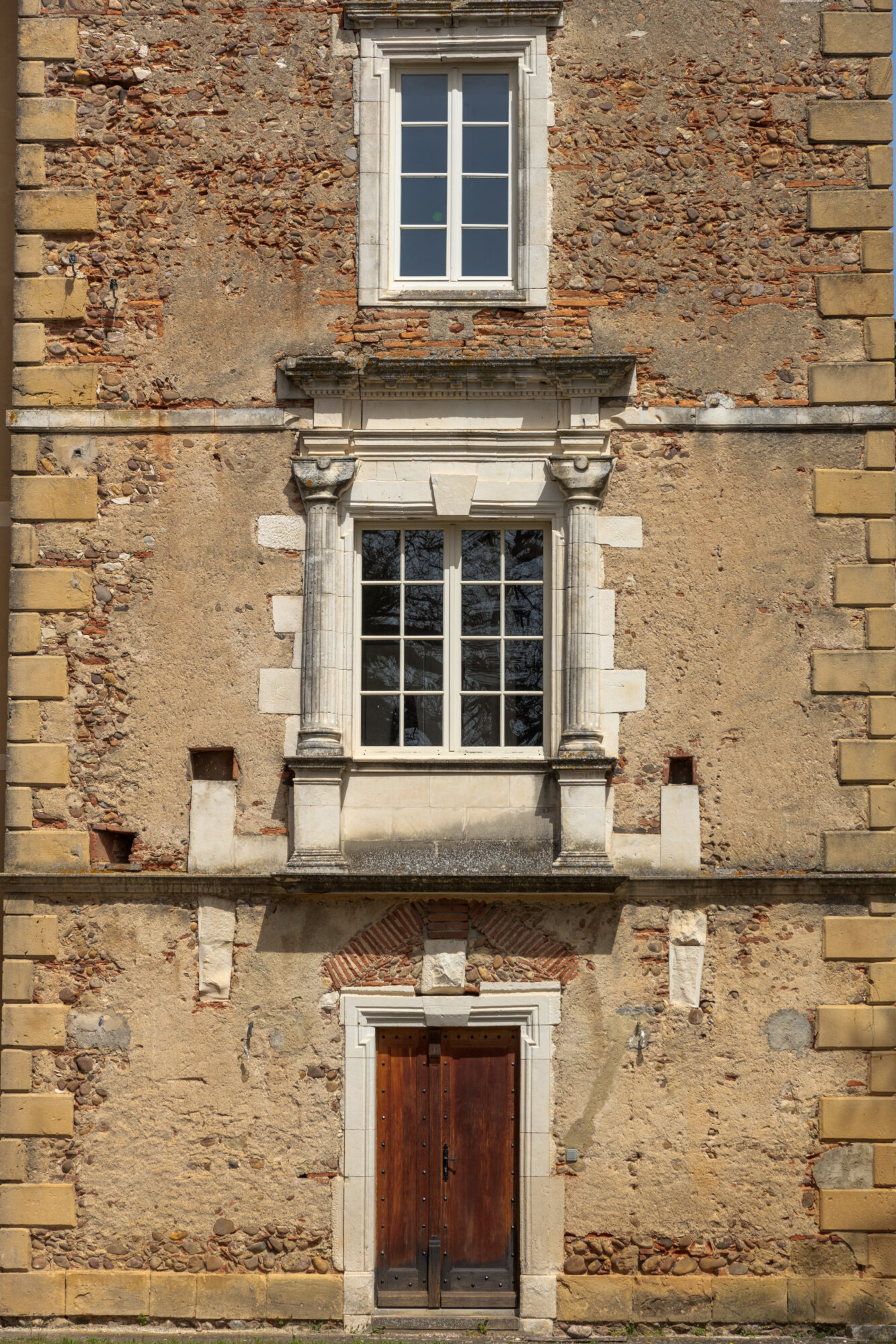 Façade ancienne en pierre avec porte en bois et fenêtre à colonnes