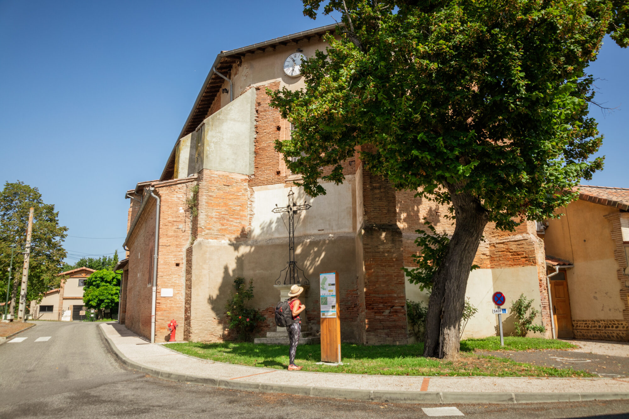 Visiteuse devant une église en brique, Office de Tourisme Cœur de Garonne