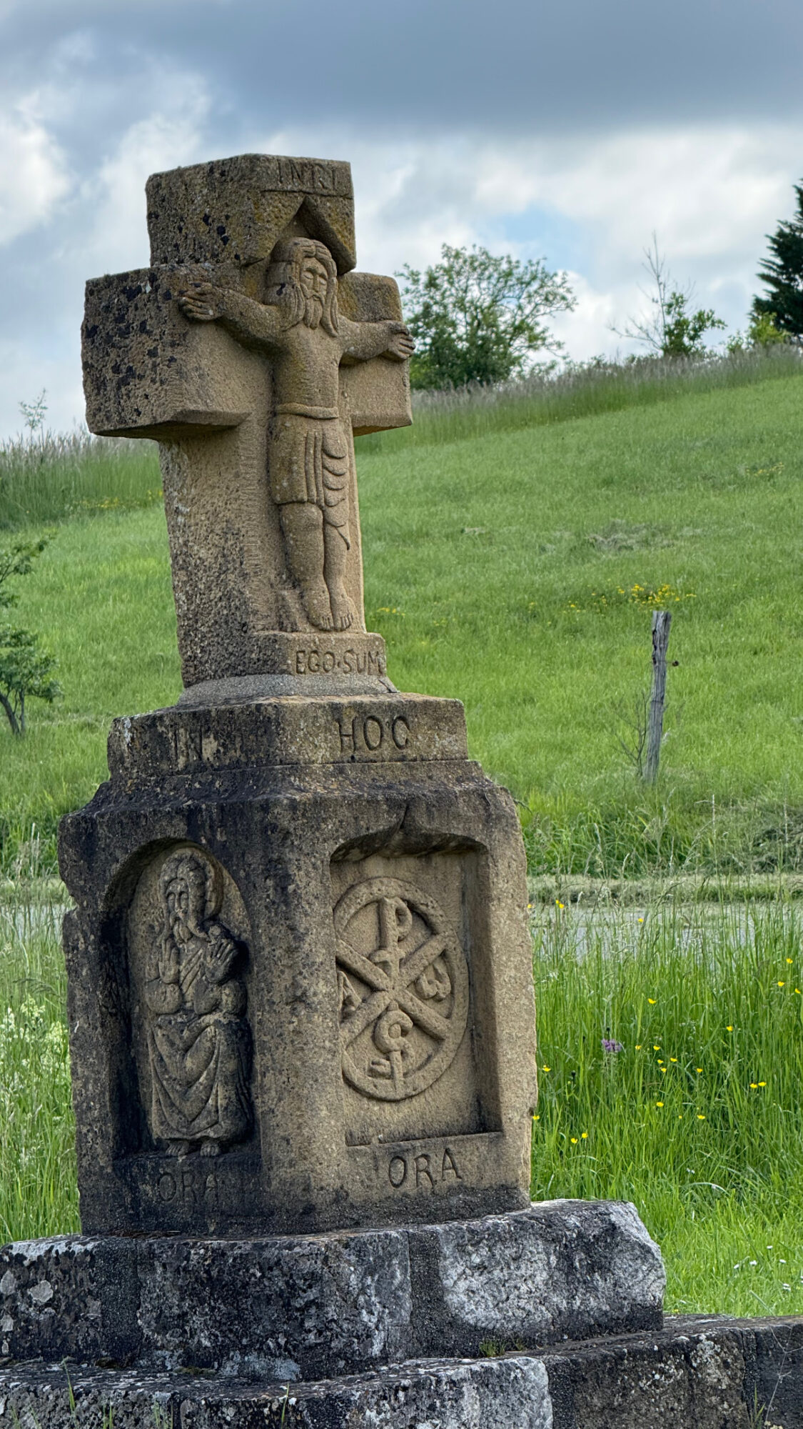 Croix en pierre sculptée avec Christ et symboles religieux