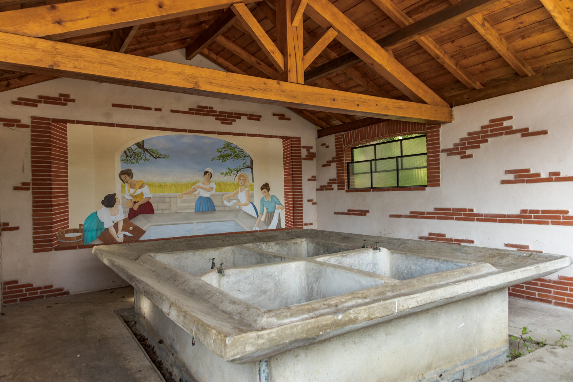 Lavoir ancien avec bassin en pierre et fresque de lavandières