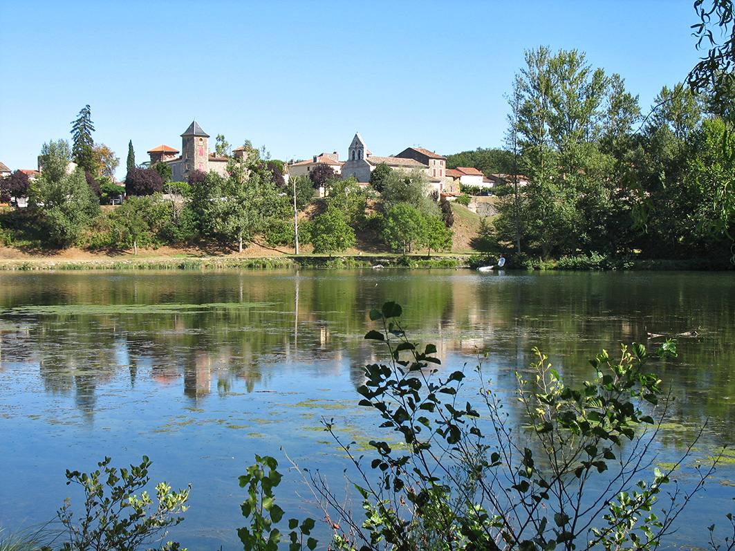 Village de Cœur de Garonne au bord d’un lac avec clocher et reflets
