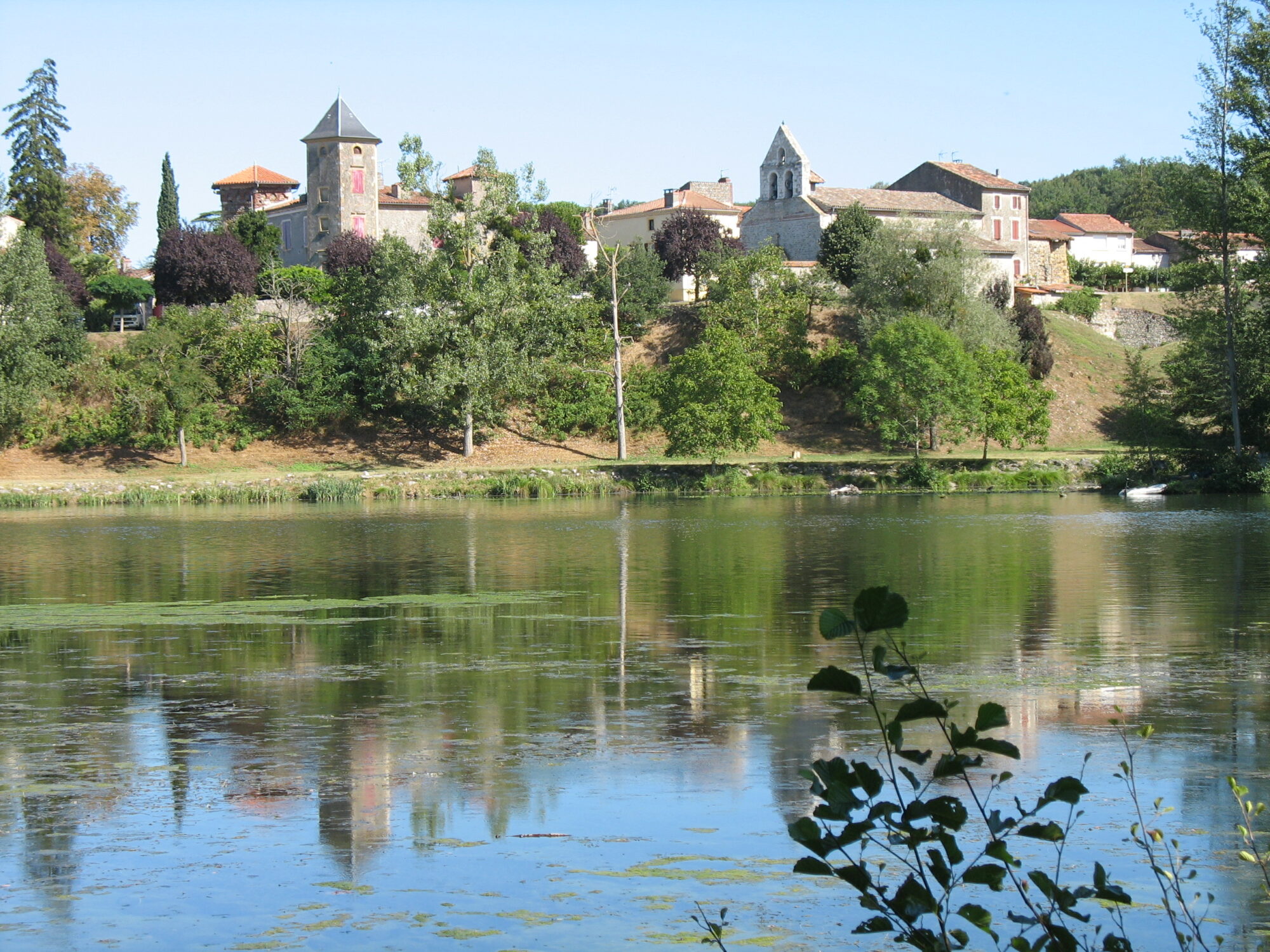 Village de Cœur de Garonne au bord d’un lac avec clocher et maisons