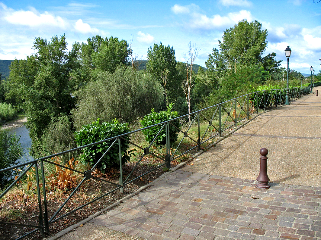 Promenade bordée de barrières et lampadaires près de la rivière