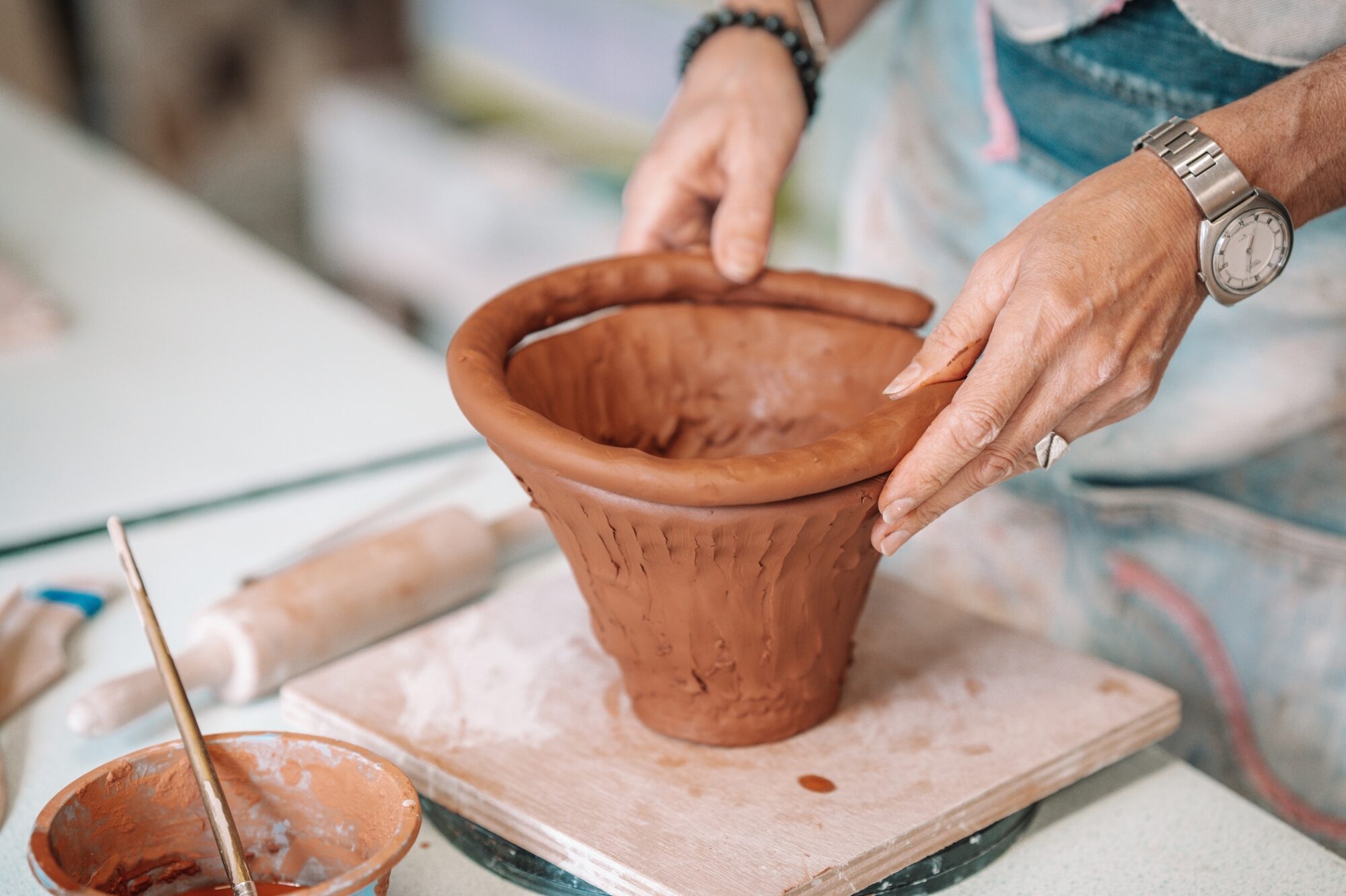 Mains façonnant un pot en argile lors d’un atelier de poterie