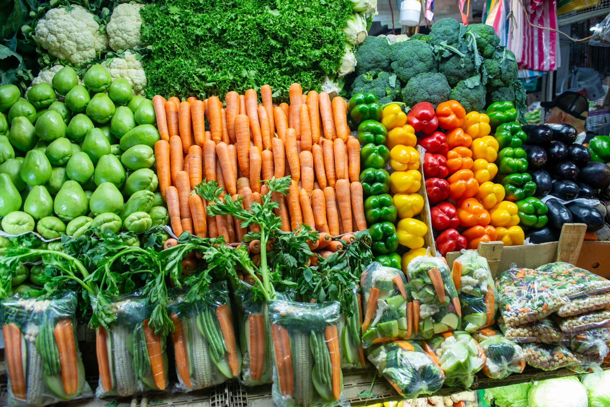 Étal de légumes frais au marché : carottes, poivrons, brocolis et chou-fleur
