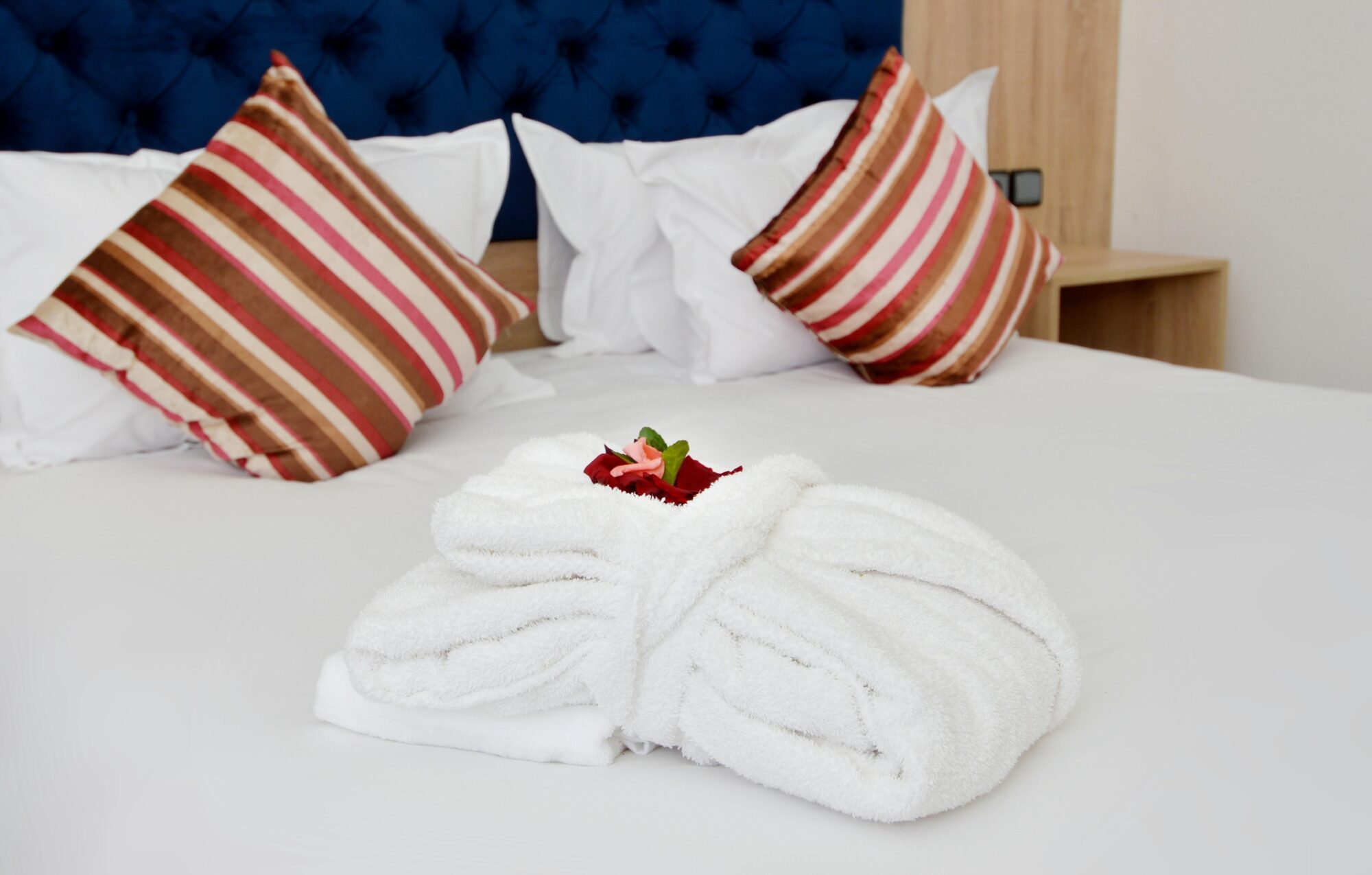 Lit double avec serviettes pliées en forme de cygne et coussins rayés