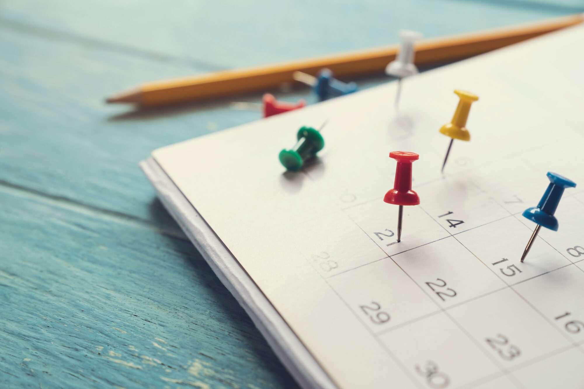 Calendrier avec punaises colorées marquant plusieurs dates importantes