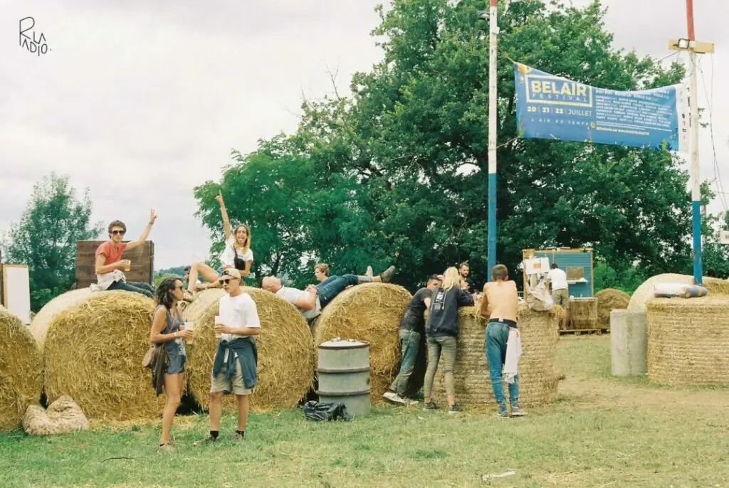 Festival Bel Air avec visiteurs assis sur des bottes de paille