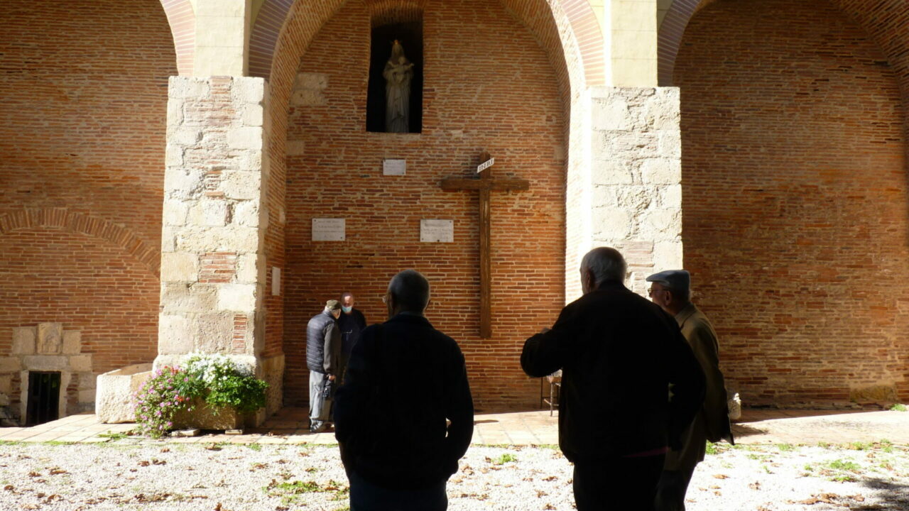 Visiteurs devant une croix dans un cloître, Office de Tourisme Cœur de Garonne