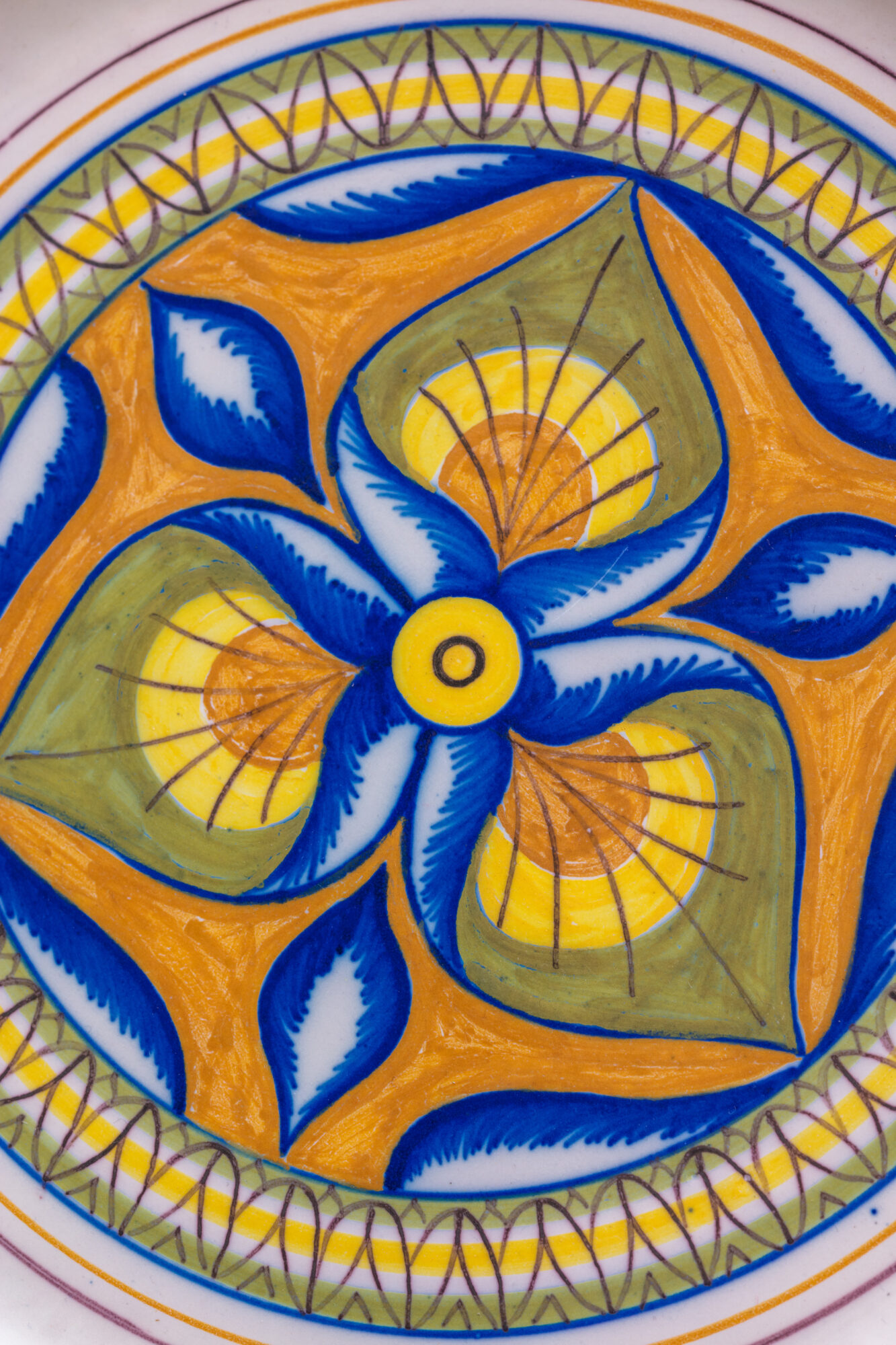 Motif floral peint sur céramique aux teintes bleues, jaunes et vertes