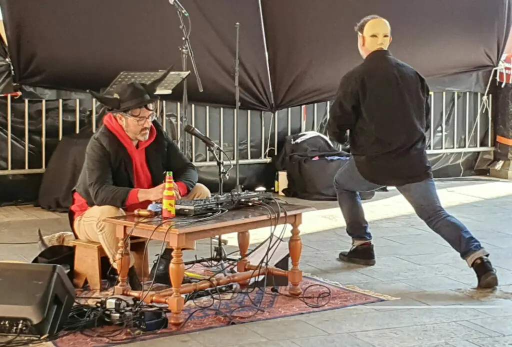 Performance scénique avec musicien assis et danseur masqué