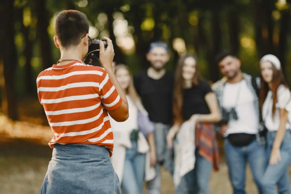 Jeune photographe prenant en photo un groupe de visiteurs en forêt