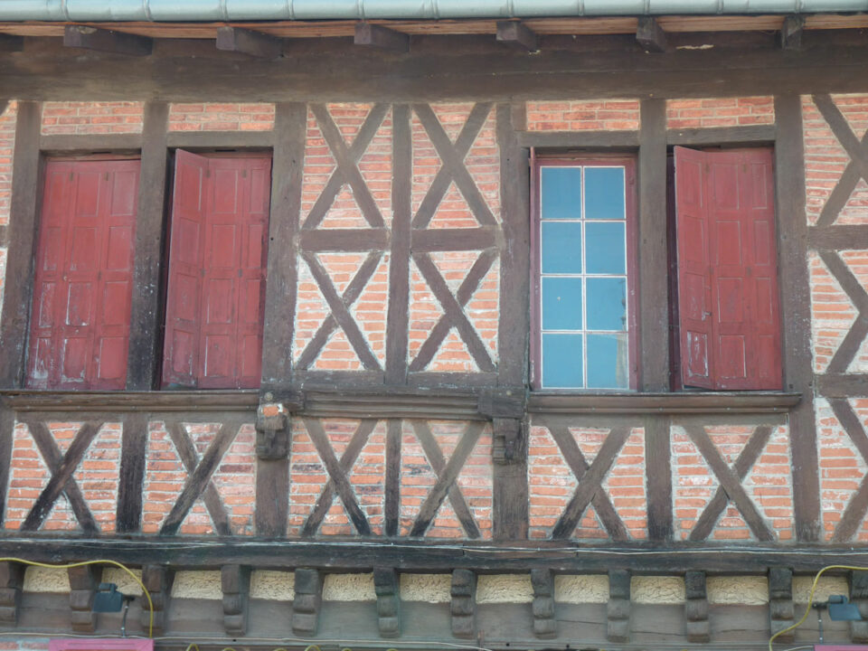 Façade à colombages avec volets rouges et fenêtre bleue
