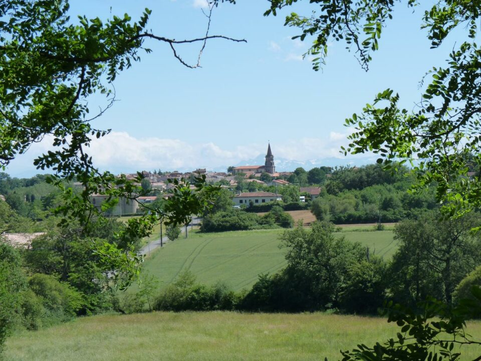 Village de Cœur de Garonne avec clocher vu à travers les arbres