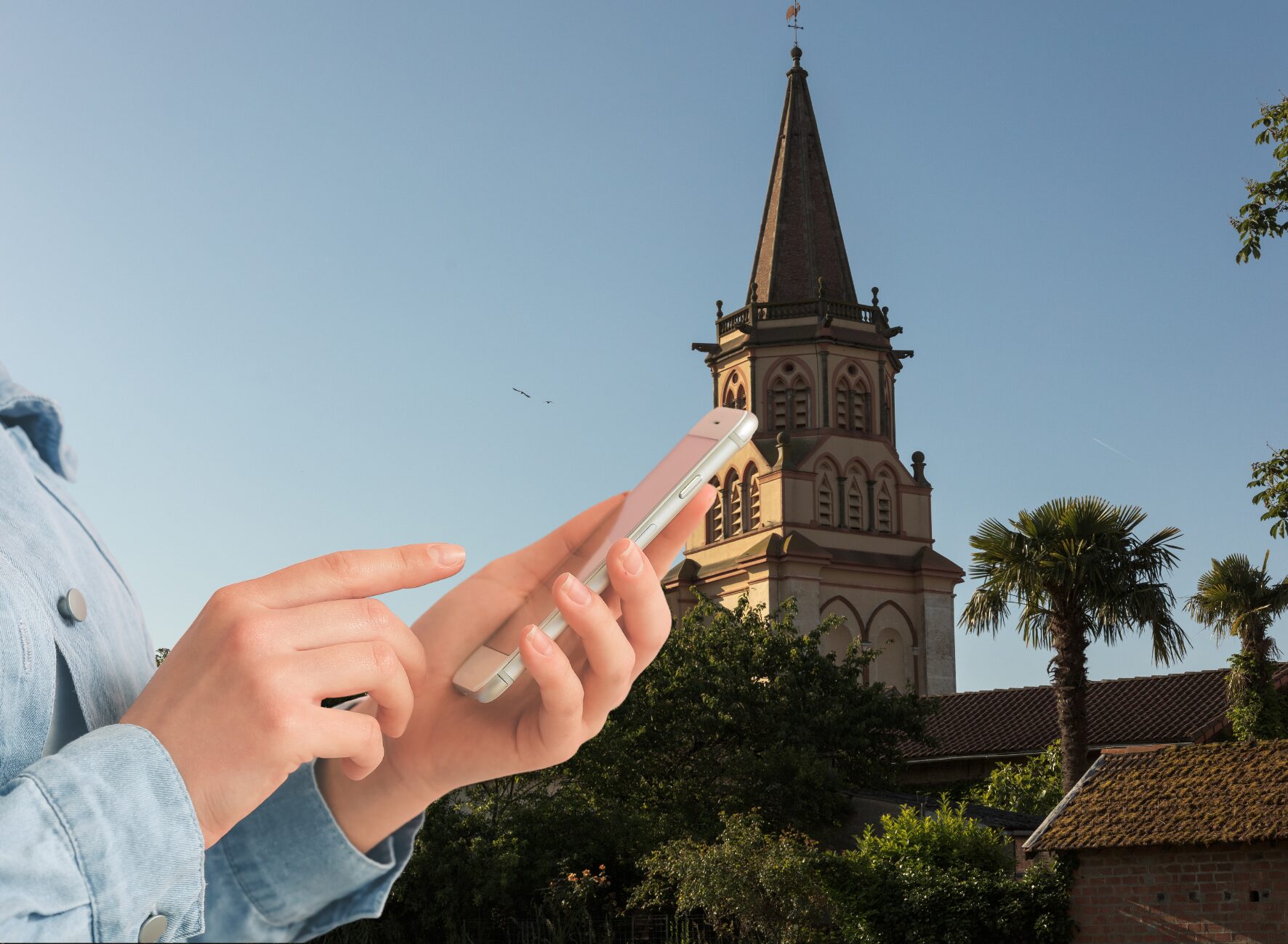 Personne utilisant un smartphone devant un clocher en Cœur de Garonne
