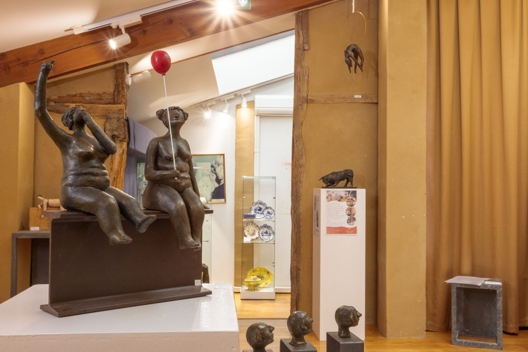 Sculpture de deux femmes assises, dont une tenant un ballon rouge