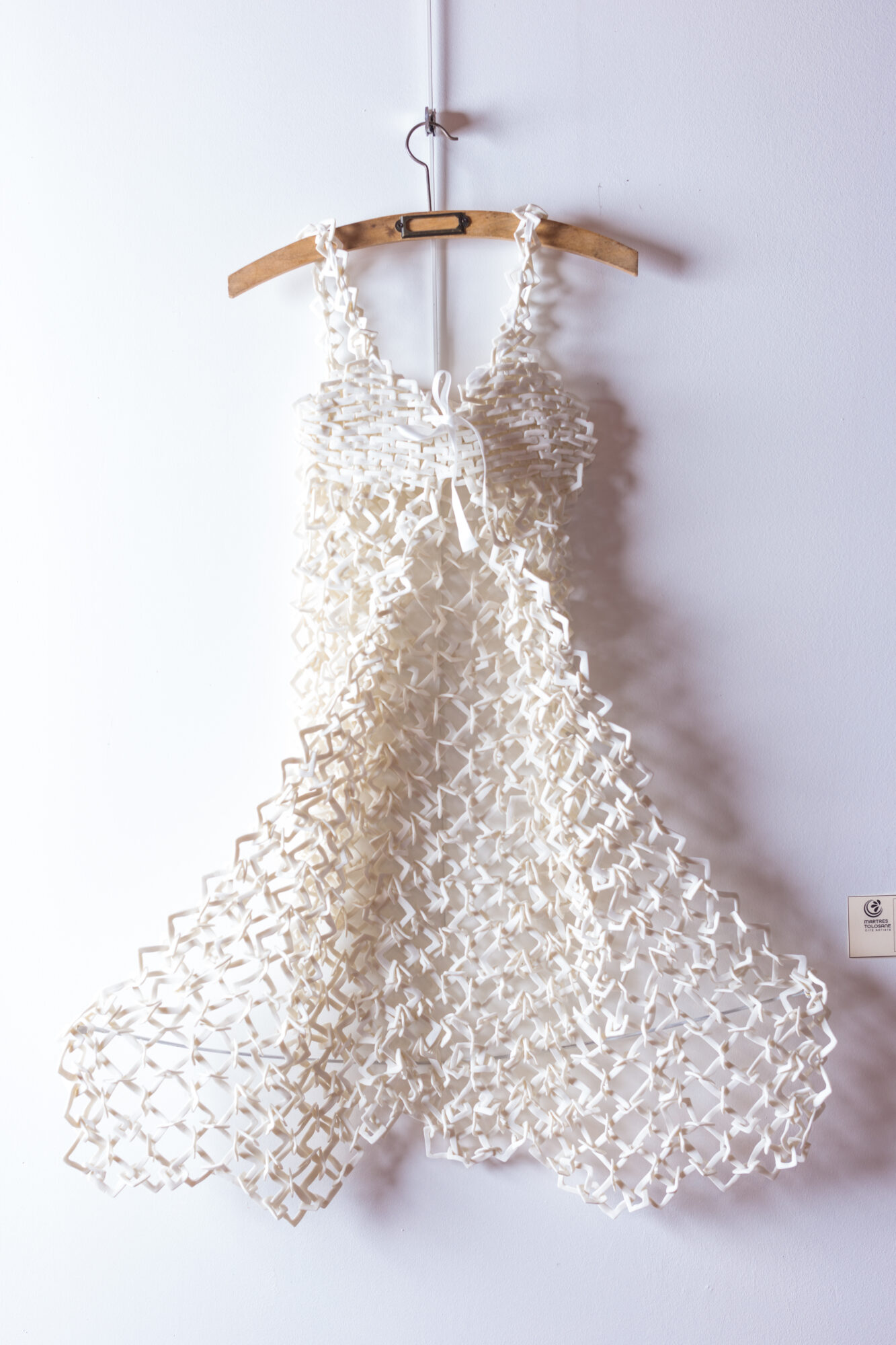 Robe blanche ajourée suspendue sur cintre, création textile artistique