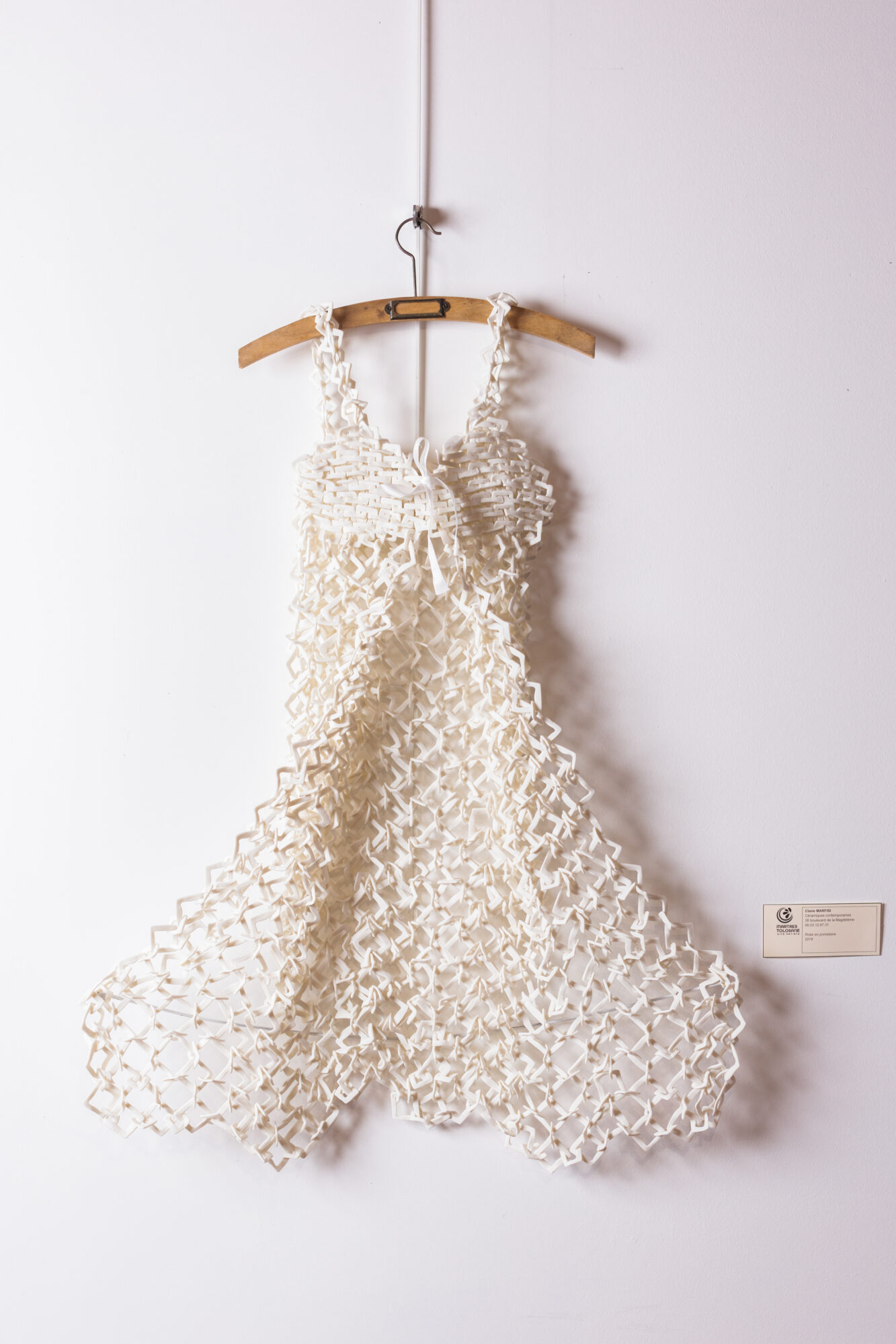 Robe blanche ajourée suspendue sur cintre en bois