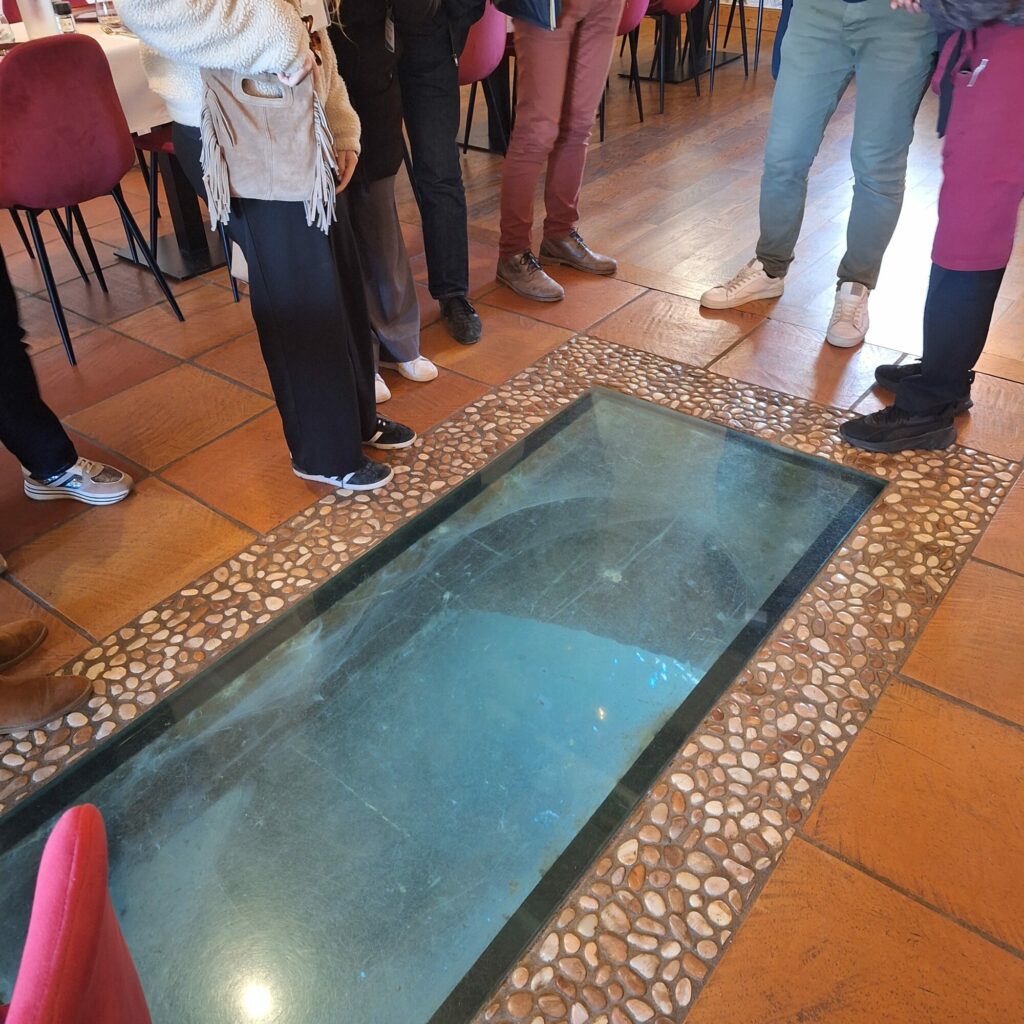 Visiteurs autour d'un puits vitré à l'Office de Tourisme Cœur de Garonne