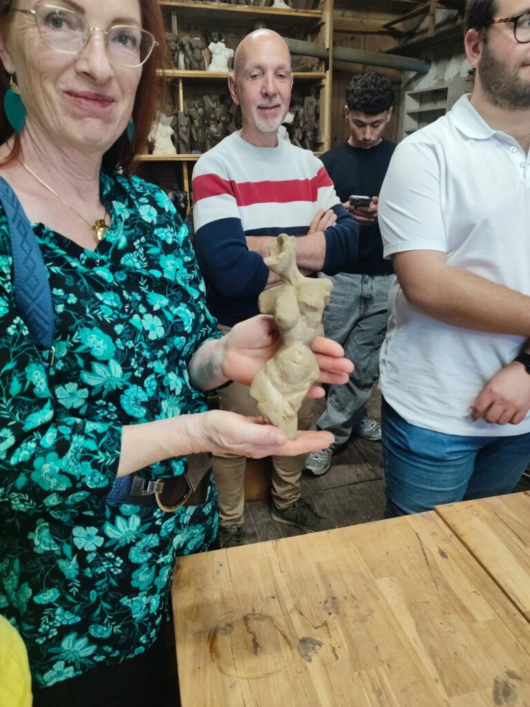 Femme présentant une sculpture en argile lors d'une visite d'atelier