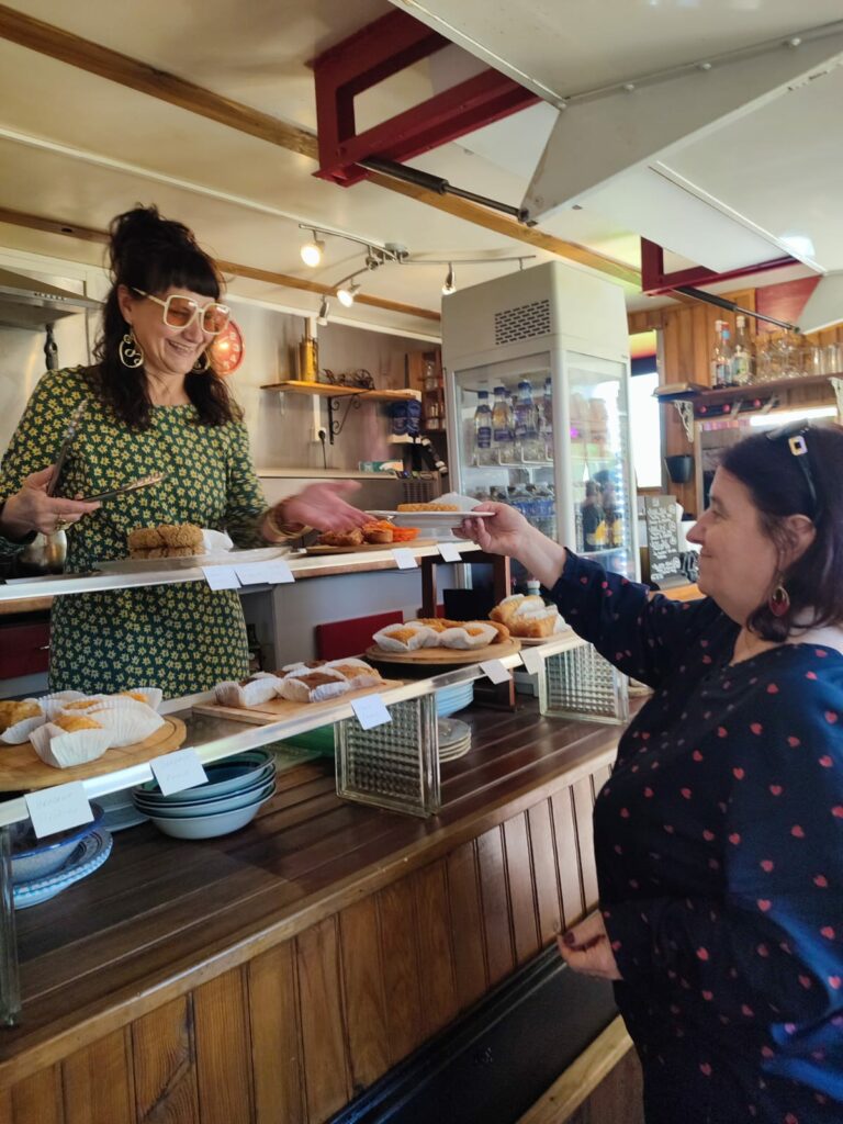 Serveuse donnant une assiette de pâtisseries à une cliente au comptoir