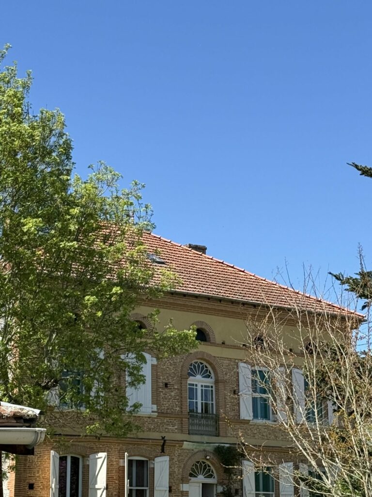 Façade de bâtisse en brique aux volets blancs à Cœur de Garonne