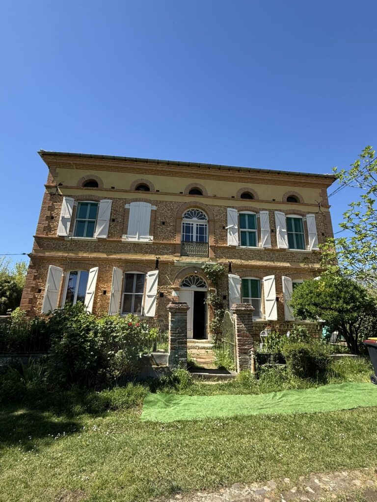 Façade de maison en brique à volets blancs, Office de Tourisme Cœur de Garonne