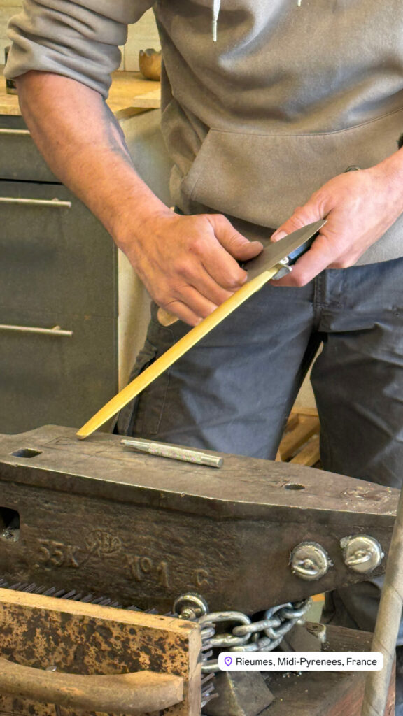 Artisan aiguisant un couteau sur une pierre à affûter à Rieumes
