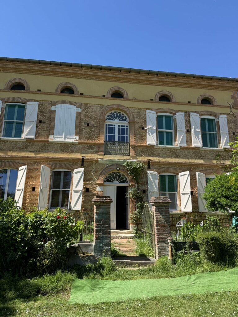 Façade de maison en brique à volets blancs, Office de Tourisme Cœur de Garonne