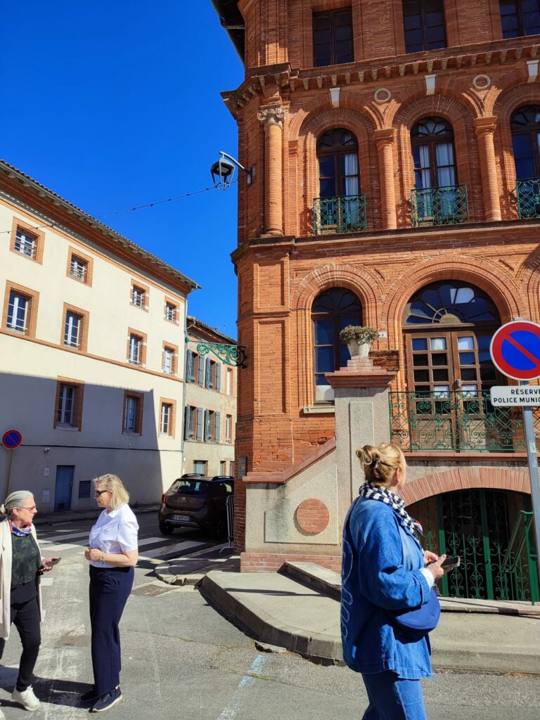 Visiteurs devant la mairie en briques, Office de Tourisme Cœur de Garonne