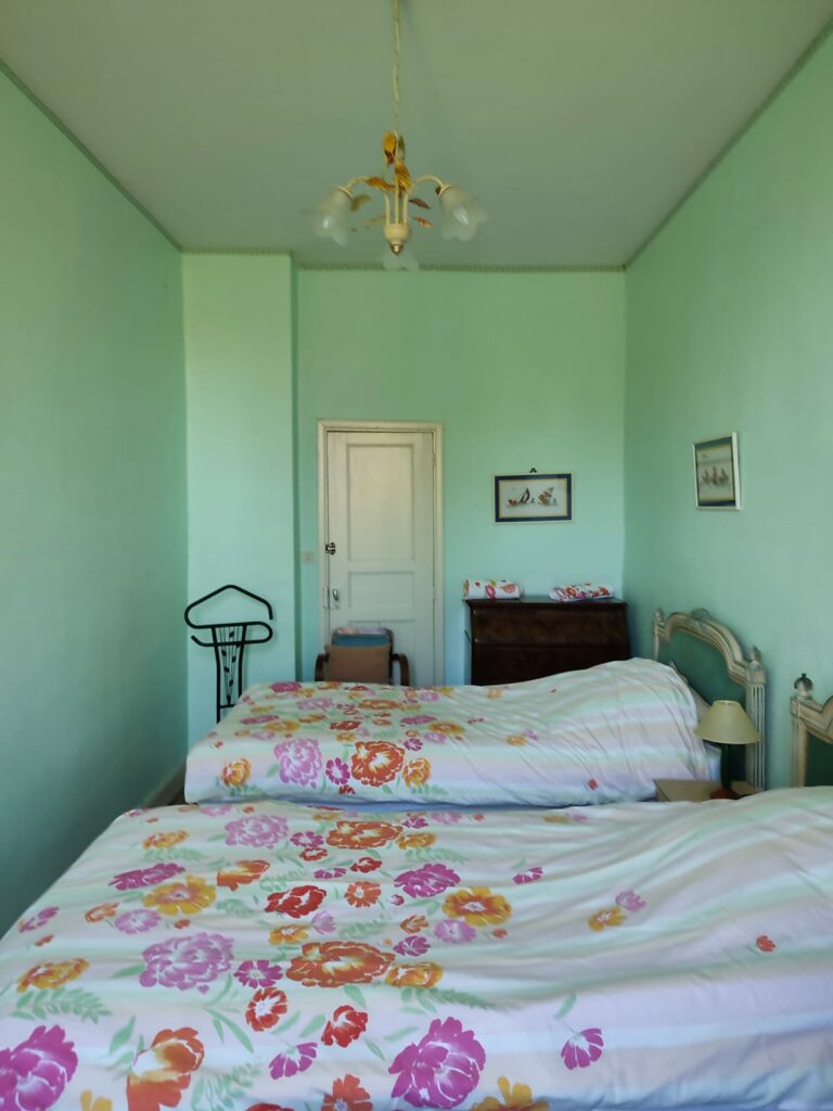 Chambre avec deux lits simples et linge de lit fleuri