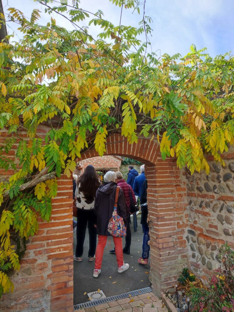 Visiteurs passant sous une arche en brique, Office de Tourisme Cœur de Garonne