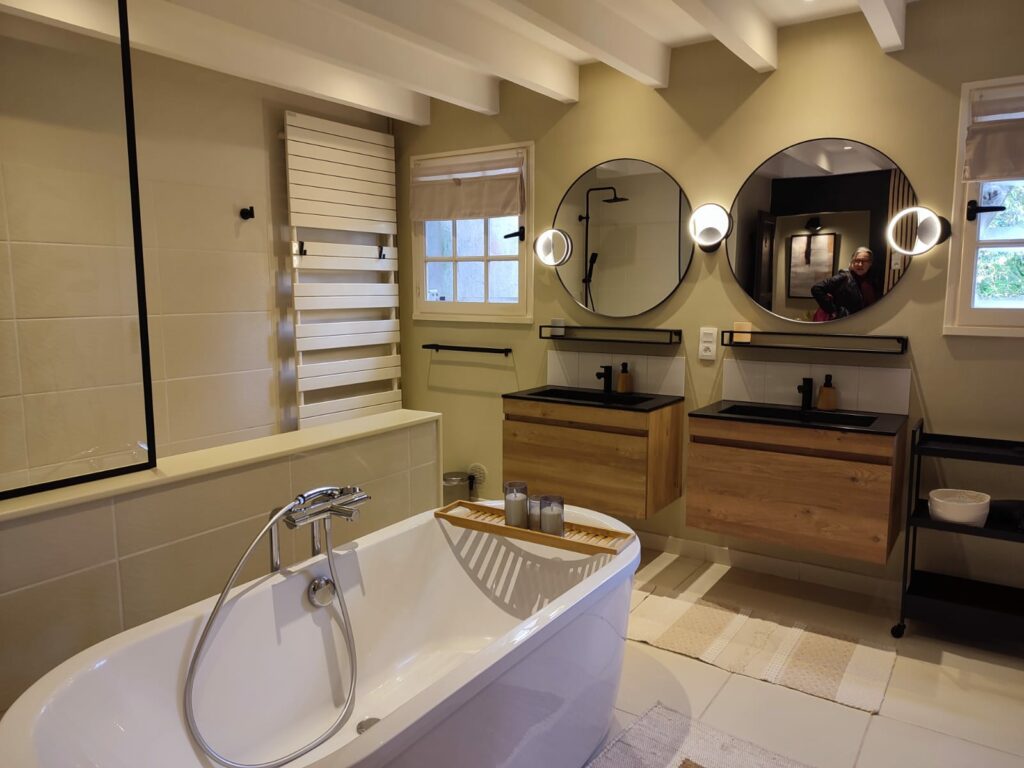 Salle de bain avec baignoire îlot, double vasque et miroirs ronds