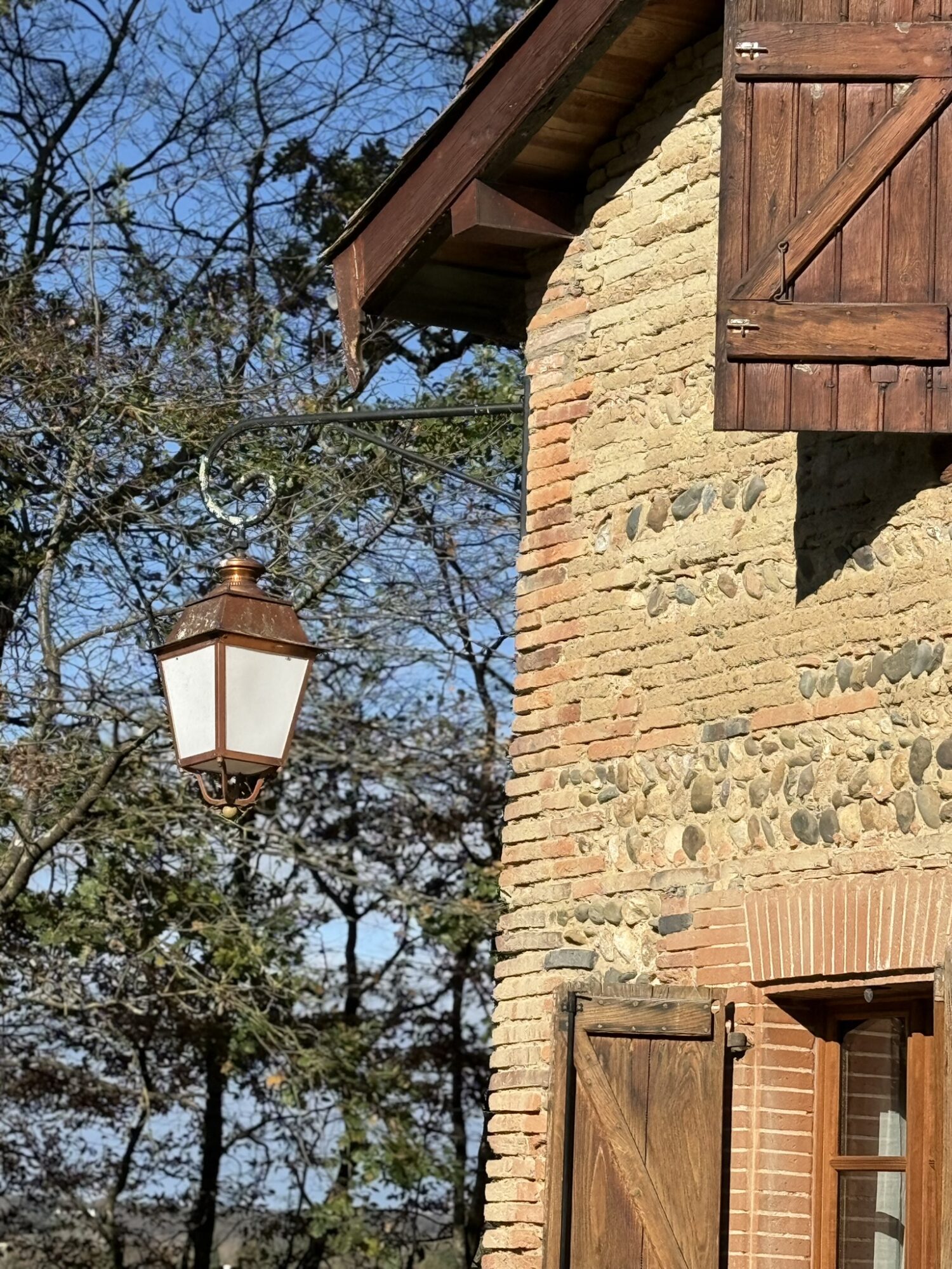 Façade en pierre et volets en bois avec lanterne, Cœur de Garonne