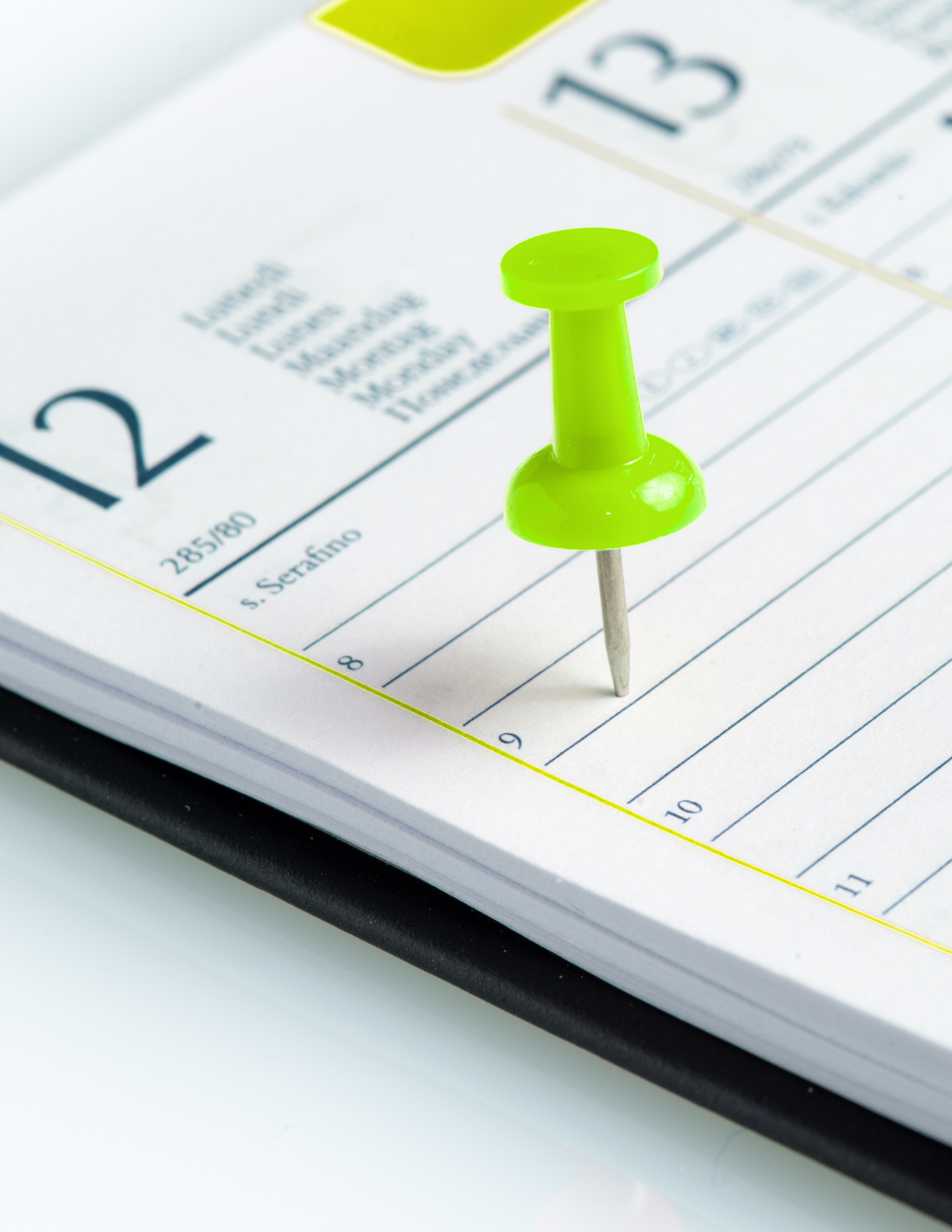 Punaise verte marquant une date sur un agenda papier