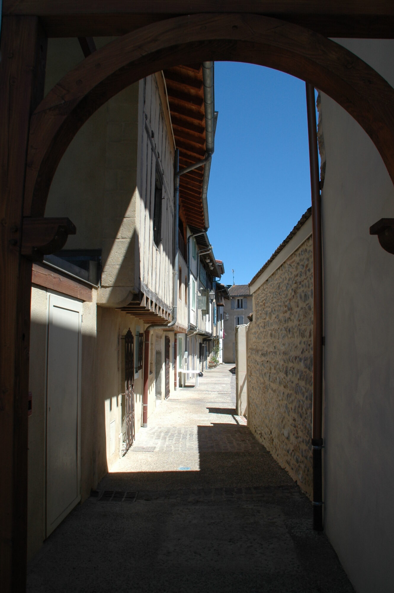 Ruelle étroite bordée de maisons à colombages et mur en pierre