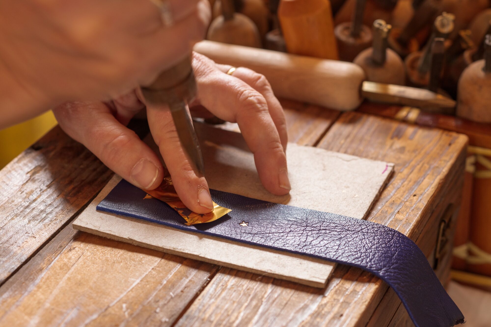 Artisan marquant une pièce de cuir à la main avec un poinçon