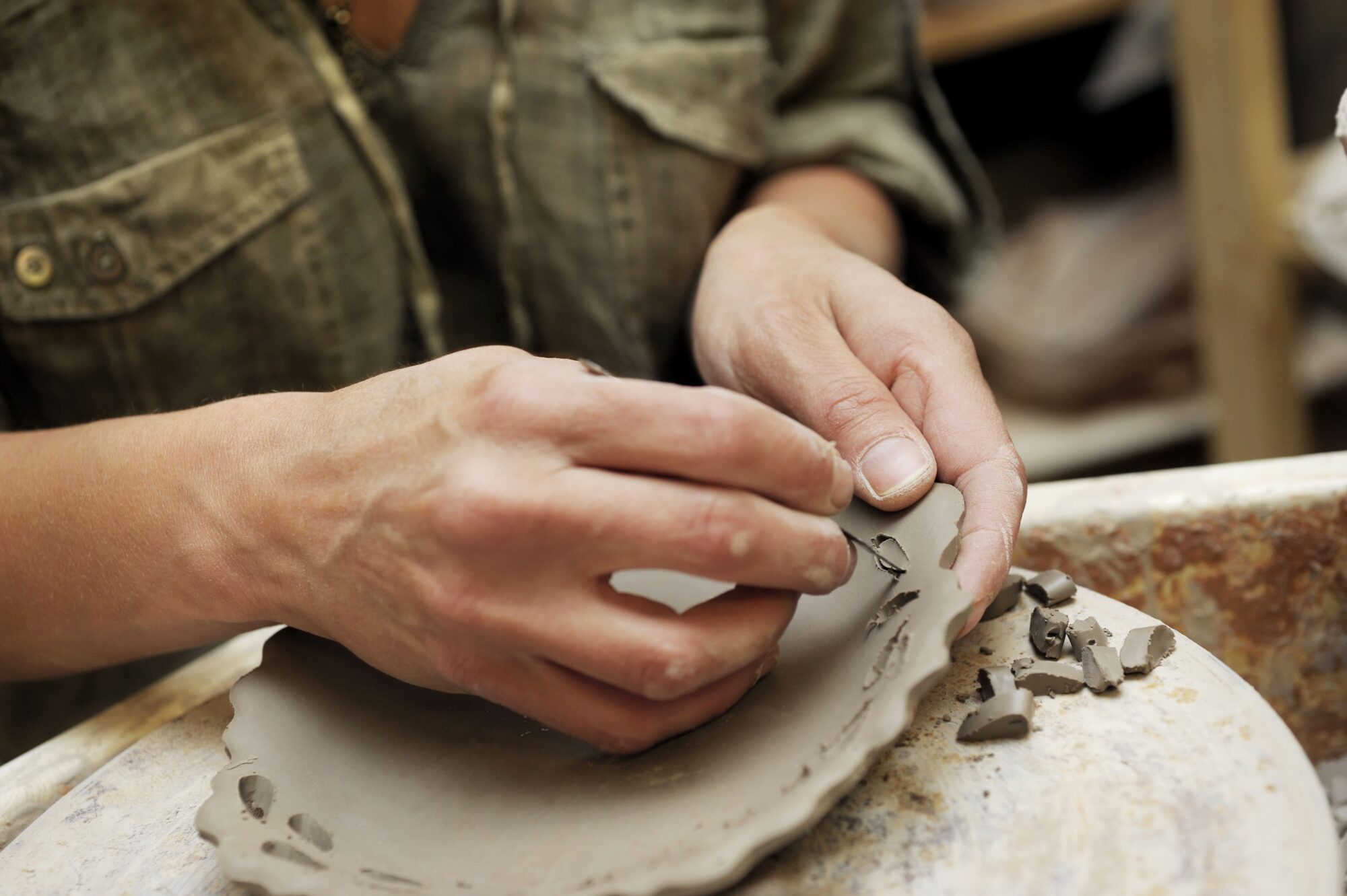 Mains façonnant une pièce en argile dans un atelier de poterie
