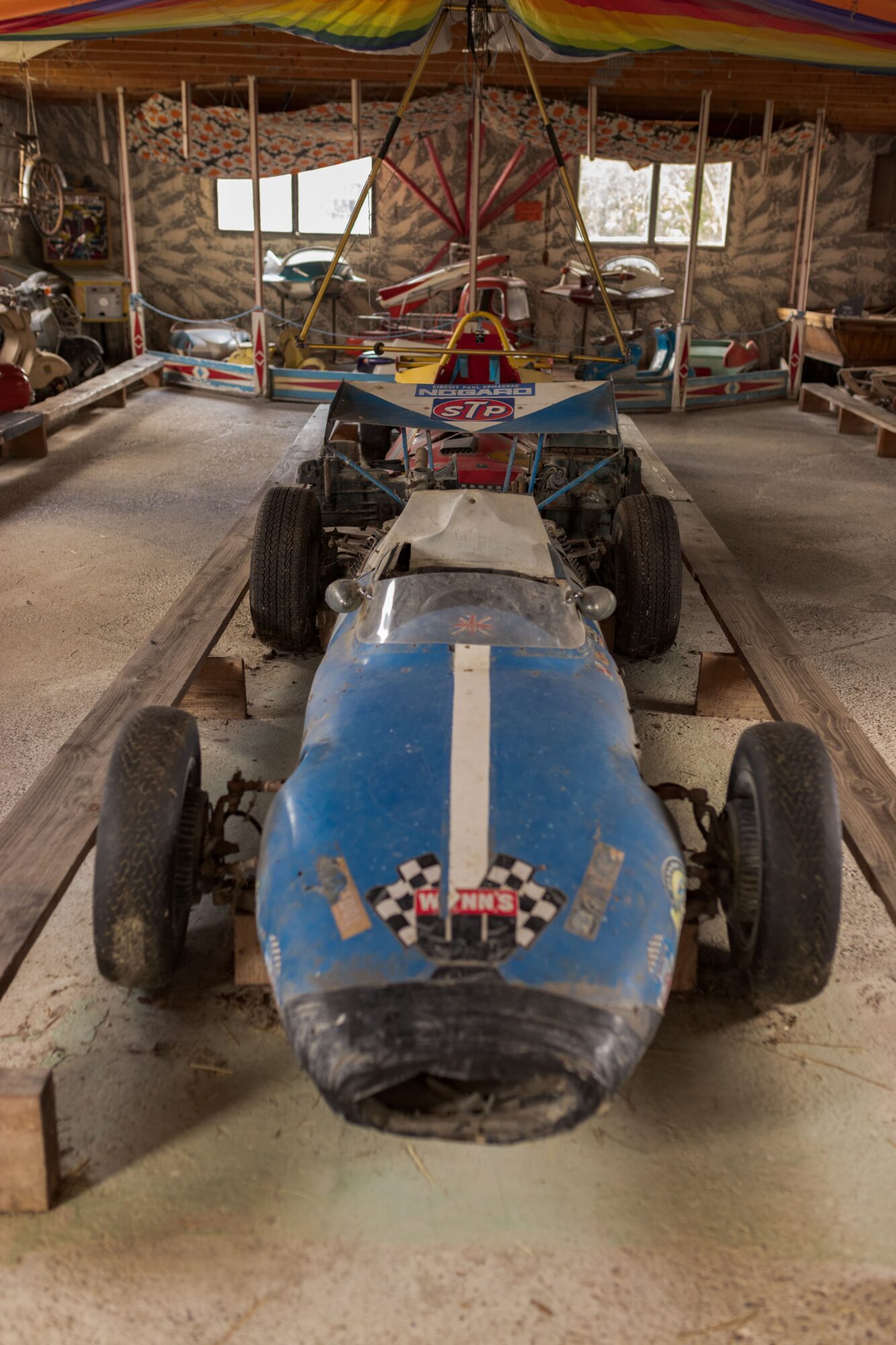 Ancienne voiture de course bleue exposée dans un manège ancien