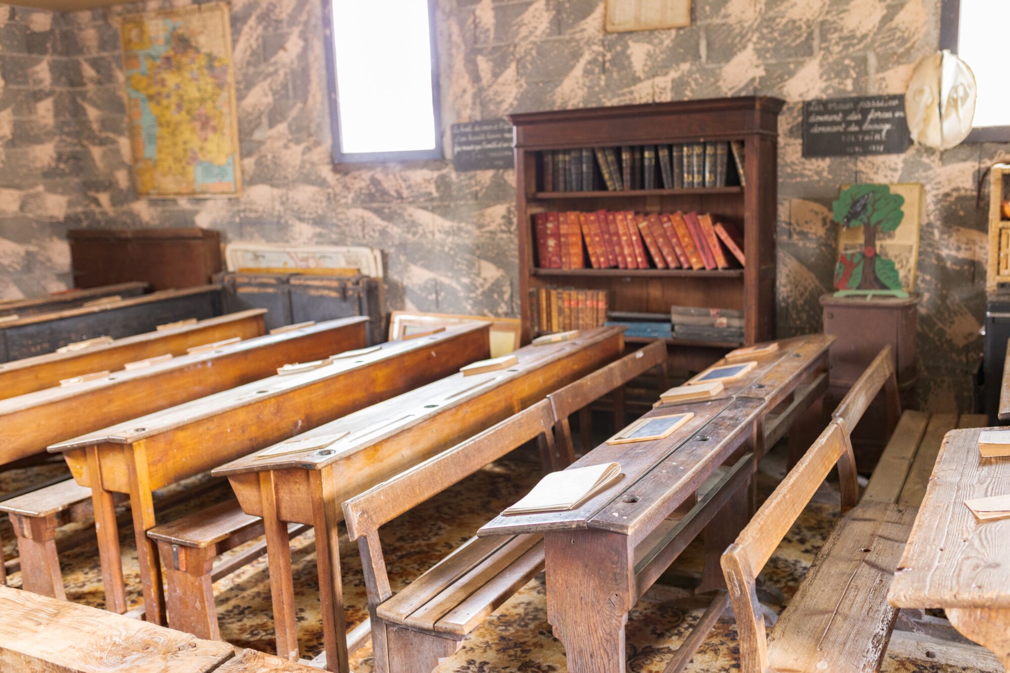 Ancienne salle de classe avec pupitres en bois et bibliothèque