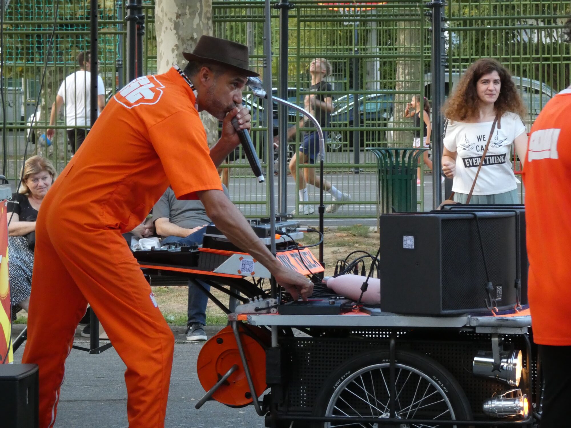 Artiste en combinaison orange chantant sur sono mobile en rue