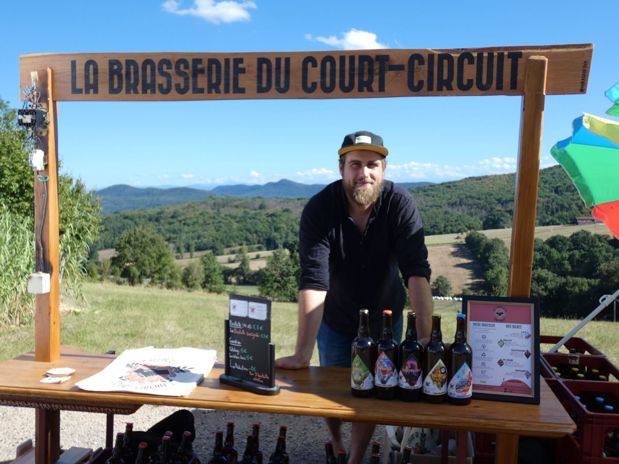 Brasseur au stand La Brasserie du Court-Circuit avec bouteilles de bière