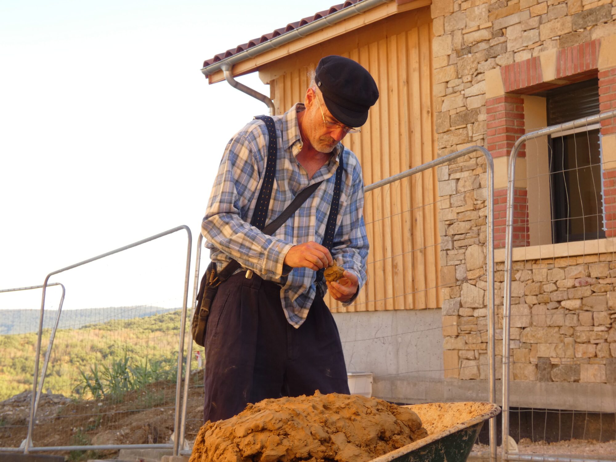 Artisan préparant de la terre pour enduit près d’un chantier