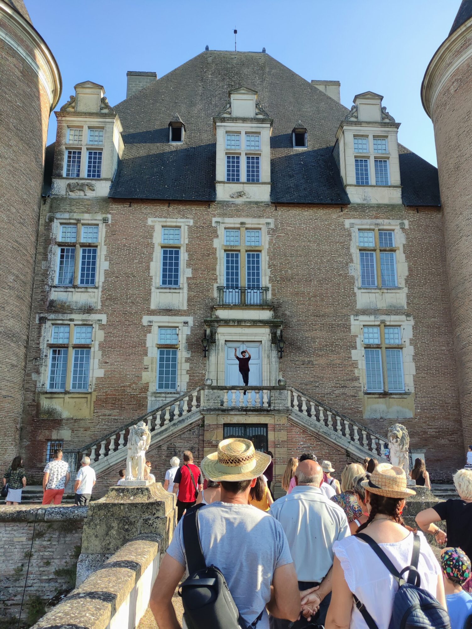 Visiteurs devant un château en brique, Office de Tourisme Cœur de Garonne